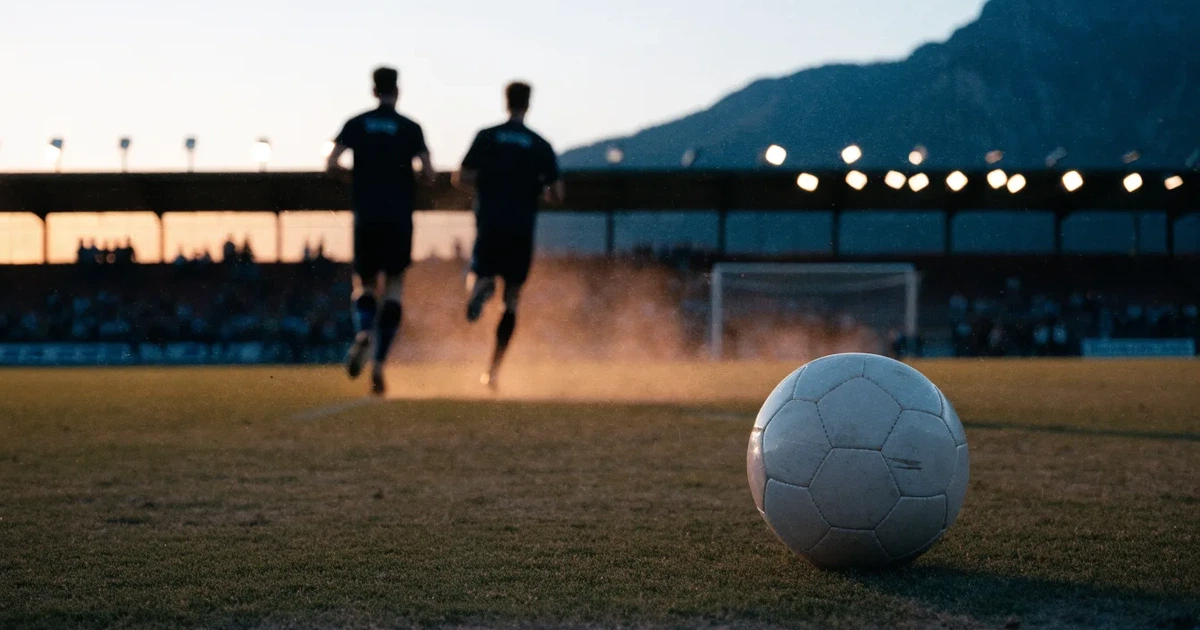 Ein Fussball auf einem staubigen Rasenstück in der Abendsonne, im Hintergrund eine hohe Bergkette